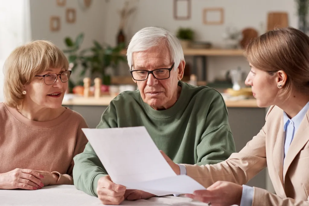 Older couple reviewing documents with an advisor at their kitchen table